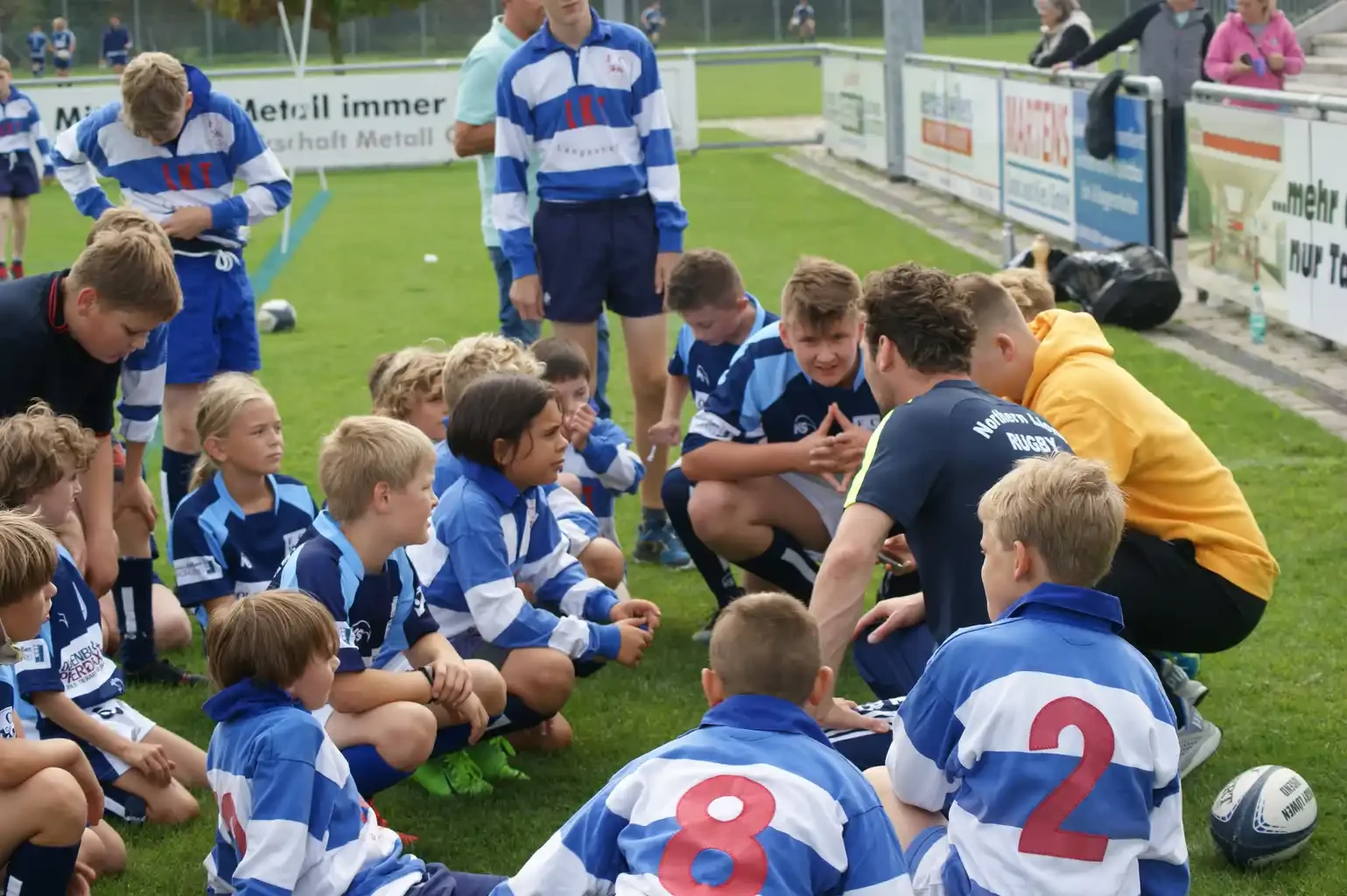 Jugendspieler im Kreis bei der gemeinsamen Besprechung mit ihren Trainern